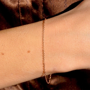 Minimalist gold-plated stainless steel thin chain bracelet worn on a woman's wrist