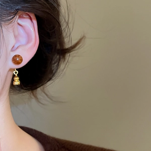 Vue macro d'une boucle d'oreille gourde en acrylique avec éclat doré sur un modèle