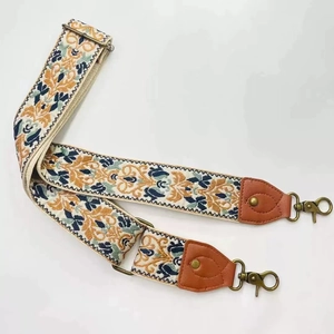 Detail of vintage embroidered bag strap with brown leather and bronze metal hooks