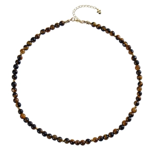 Macro detail of natural tiger eye beads and gold lobster clasp with heart pendant