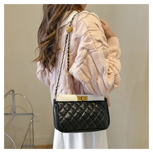 Detail of quilted shoulder bag with gold-tone chain strap and ball adjustment buckle