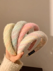 Détail de quatre serre-têtes en peluche douce en jaune pastel, bleu, rose et arc-en-ciel