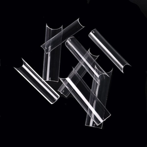 Close-up of extra long clear C-curve false nail tips with white size markers on black background