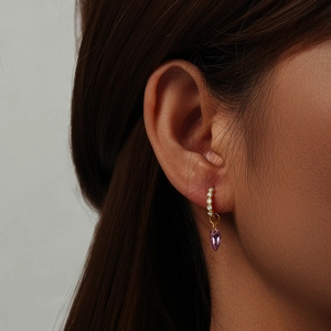 Close-up of vintage 18K gold heart-shaped purple crystal earring worn by a model