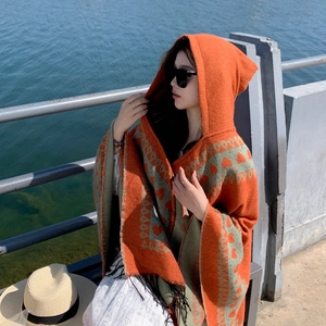 Détail du poncho ethnique orange à capuche avec motifs de cœurs et franges noires