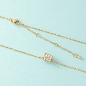 Detail of gold titanium steel necklace featuring a triple-row crystal cylinder pendant