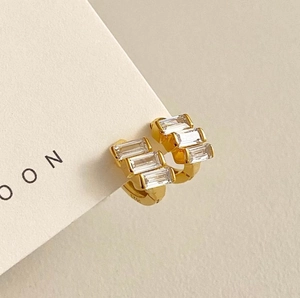 Detail of gold-plated 925 silver hoop earrings with three vertical baguette-cut zircons