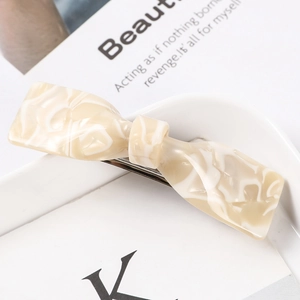 Detail of a marble textured acetate bow hair claw clip on a white ceramic plate