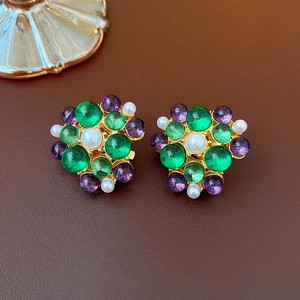 Detail of vintage gold earrings with colorful gemstones and pearls on leather background