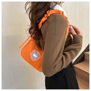 Detail of orange nylon shoulder bag with ruffled strap and heart rabbit patch