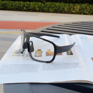 Outdoor lifestyle shot of matte black cycling sunglasses on a magazine in a park setting