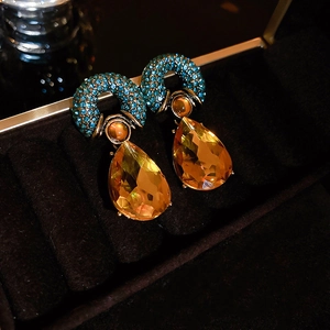 Macro shot of vintage water drop earrings with amber gemstones and teal crystal accents