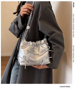 Silver bow shoulder bag in soft leather finish styled with metallic chain on model