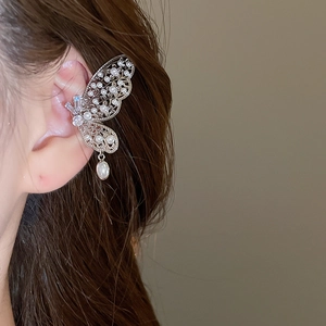 Détail de l'oreille avec un bijou papillon ajouré serti de perles et de cristaux