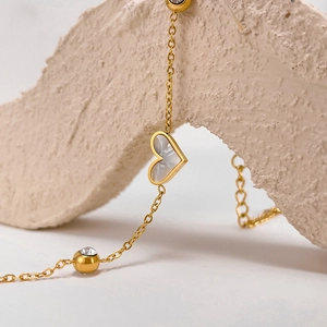 Detail of gold heart pendant with white mother of pearl and crystal accents on stone