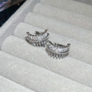 Macro shot of silver zircon ear cuff featuring baguette cut stones on grey velvet