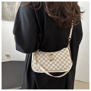Detail of cream monogram crescent bag with golden M logo and chain strap on shoulder