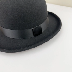 Detailed close-up of a classic black wool felt bowler hat with a grosgrain ribbon band