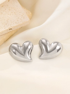 Close-up of polished heart-shaped stainless steel earrings on elegant satin fabric