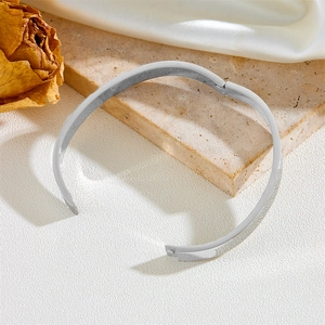 Silver stainless steel bangle displayed on a stone steps with elegant fabric backdrop