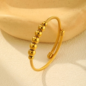 Detailed close-up of a gold-plated twisted open cuff bracelet with seven polished beads