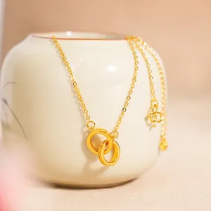 Elegant 24K gold double interlocking ring necklace hanging on a ceramic vase