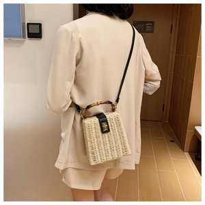 Detail of hand-woven straw crossbody bag with bamboo handle and gold metal clasp