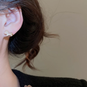 Close-up of elegant gold horse-shaped stud earrings with sparkling rhinestones on model