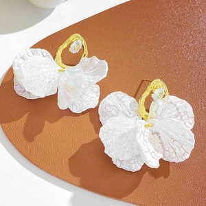 Vue détaillée de pétales de fleurs en acrylique irisé blanc et boucles d'oreilles dorées