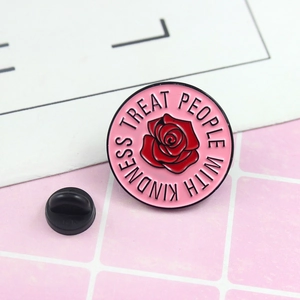 Detail of pink metal enamel pin with red rose and Treat People With Kindness text