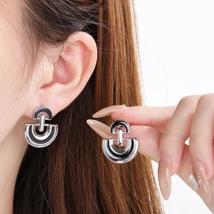 Detail of silver D-shaped stainless steel earring with black enamel on model's ear