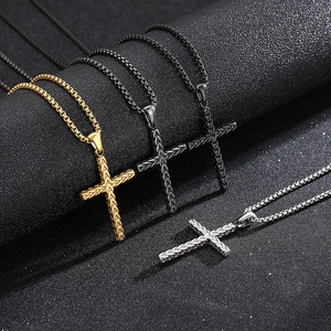 Three-color stainless steel cross pendants with box chains on a textured black surface