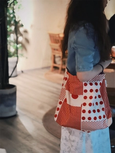 Détail du sac fourre-tout en toile à pois rouges et blancs porté à l'épaule pour le loisir