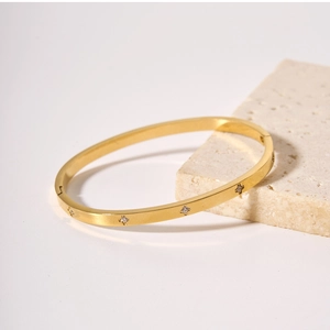 Dettaglio macro del bracciale in acciaio dorato con delicati zirconi a forma di stella