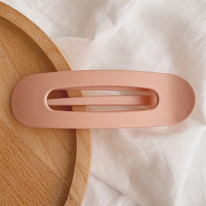 Detailed view of matte peach pink hollow rectangular hair clip on a wooden tray