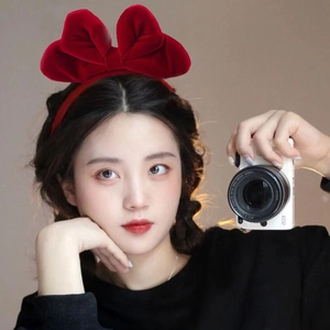 Elegant red velvet headband with large bow shown on a model for a sweet festive look