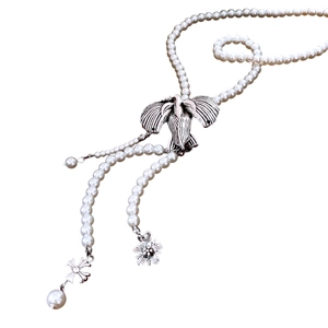 Vintage pearl necklace with silver bird pendant and floral charms in a minimalist style
