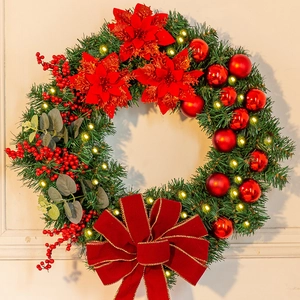 Detail of Christmas wreath with red poinsettia, velvet bow, and warm LED lights