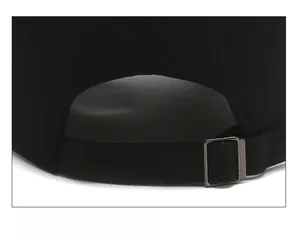 Gros plan sur la boucle métallique réglable et la sangle en coton d'une casquette noire