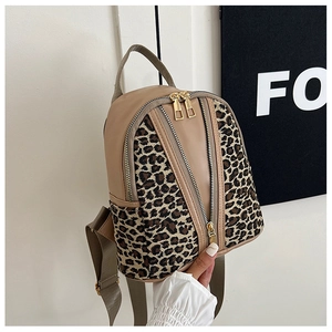 Detailed view of leopard print and tan leather backpack with dual front zipper pockets