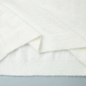 Close-up of soft white knitted sweater fabric with fuzzy wool texture and ribbed hem detail