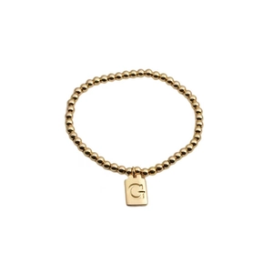 Détail d'un bracelet à perles plaqué or avec un pendentif carré portant la lettre G