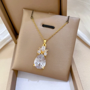 Détail d'un pendentif en cristal goutte d'eau sur collier doré sur fond de soie blanche