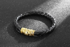 Close-up of black braided leather bracelet with golden skull magnetic clasp details