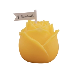 Vibrant yellow rose-shaped scented candle with decorative paper flag on white background