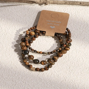 Detailed macro of vintage tiger eye beaded bracelets with a gold heart charm on a card