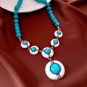 Détail macro de perles turquoise et pendentif doré sur fond de soie pour bijoux