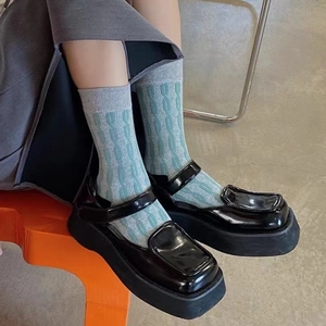Détail de chaussettes torsadées vertes portées avec des chaussures Mary Jane noires