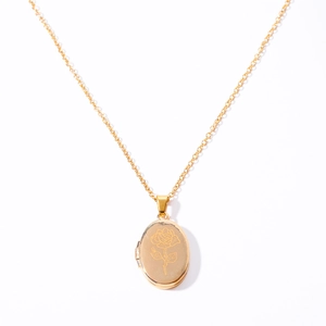 Macro detail of golden oval locket necklace featuring an intricate engraved rose pattern