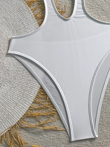 Close-up of white high-cut one-piece swimsuit with detailed stitching and straw hat